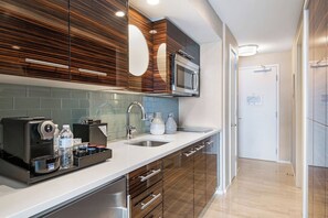 A modern kitchen with a built-in microwave, stainless steel sink, and wooden cabinets. - Conrad Private Residence | Ocean & Intracoastal Views | 2 Queens (Fort Lauderdale)