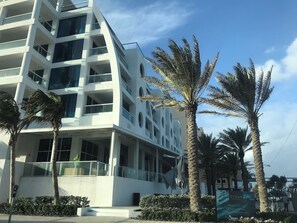 A modern multi-story hotel with balconies, palm trees, and a clear sky. - Conrad Private Residence | Ocean & Intracoastal Views | 2 Queens (Fort Lauderdale)