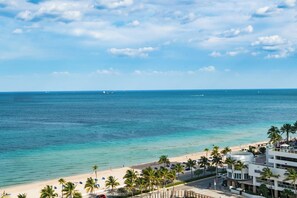 Un hotel frente al mar con vistas a la playa, palmeras y cielo despejado.