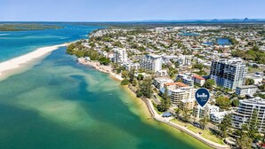 An aerial view of a coastal area with a beach, residential buildings, and a marina. - Golden Views Hideaway - Beachside Apartment (Golden Beach)