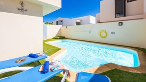 A swimming pool with a blue edge, a lounge chair, a sun lounger, and a small garden area. - Villa Paula - Three Bedroom Villa, Sleeps 6 (Costa Teguise)