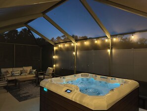 A hot tub under a covered patio with string lights, a sofa, and a coffee table. - "The River House" Dock, Kayaks, Hot Tub + so much more (Crystal River)