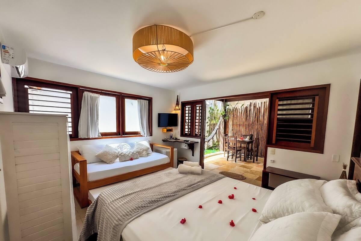 A bedroom with a bed, a desk, and a seating area with a table and chairs.