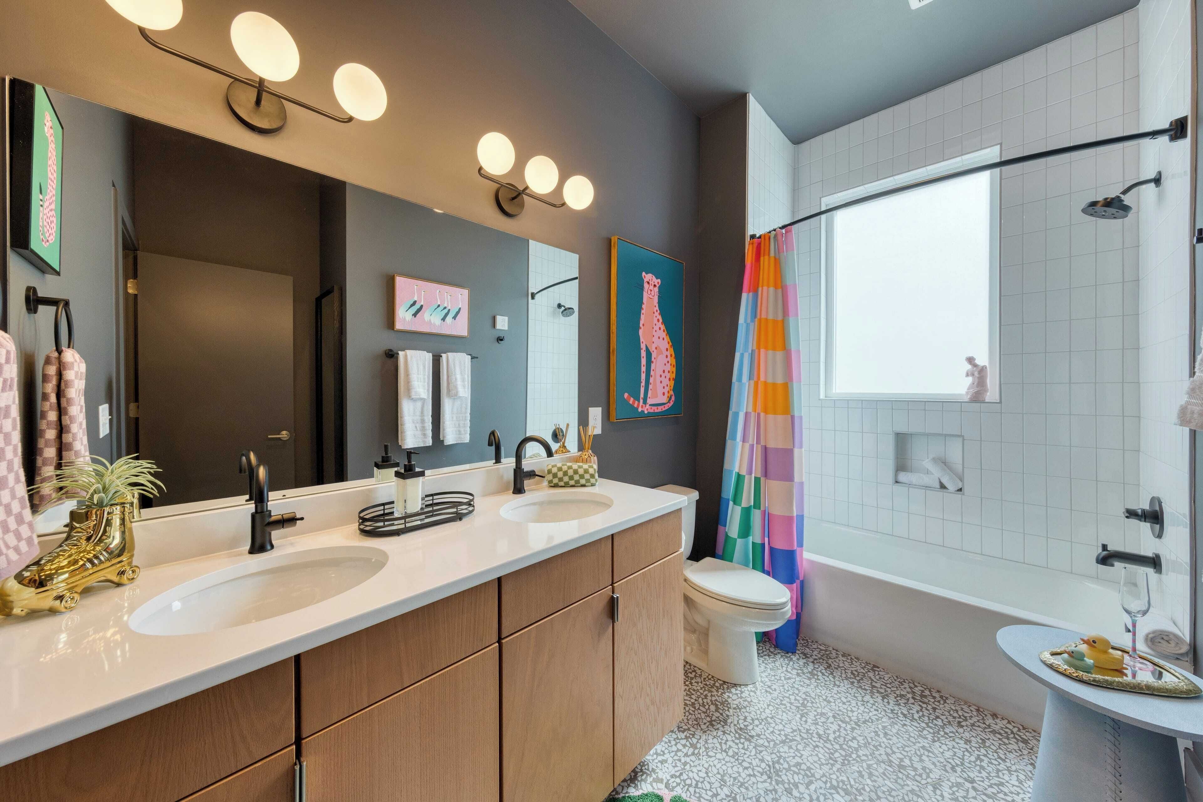 Une salle de bain moderne avec deux vasques, un grand miroir et un espace douche.