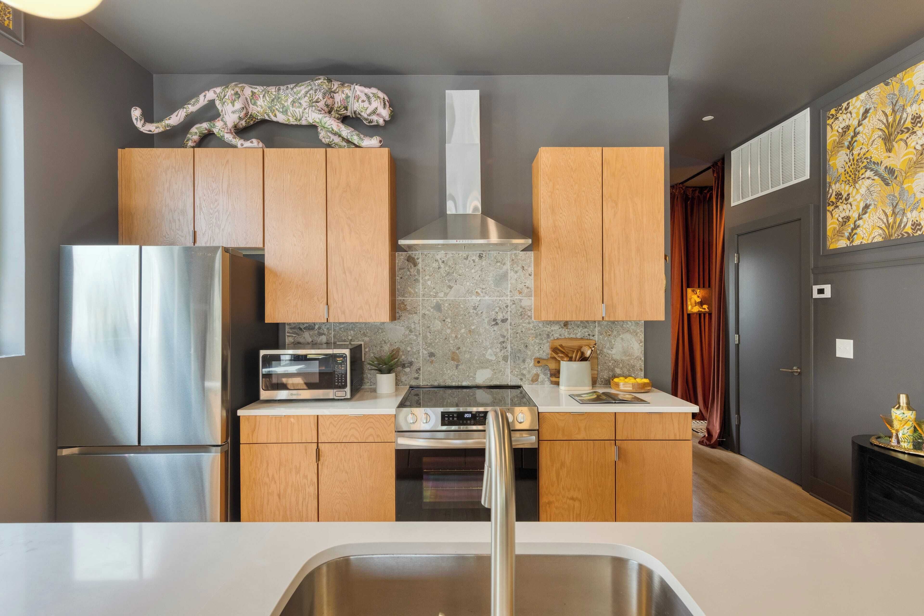 A modern kitchen with wooden cabinets, stainless steel appliances, and a decorative animal sculpture.