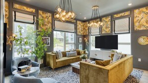 A modern living room with a sofa set, a coffee table, a TV, and decorative plants.