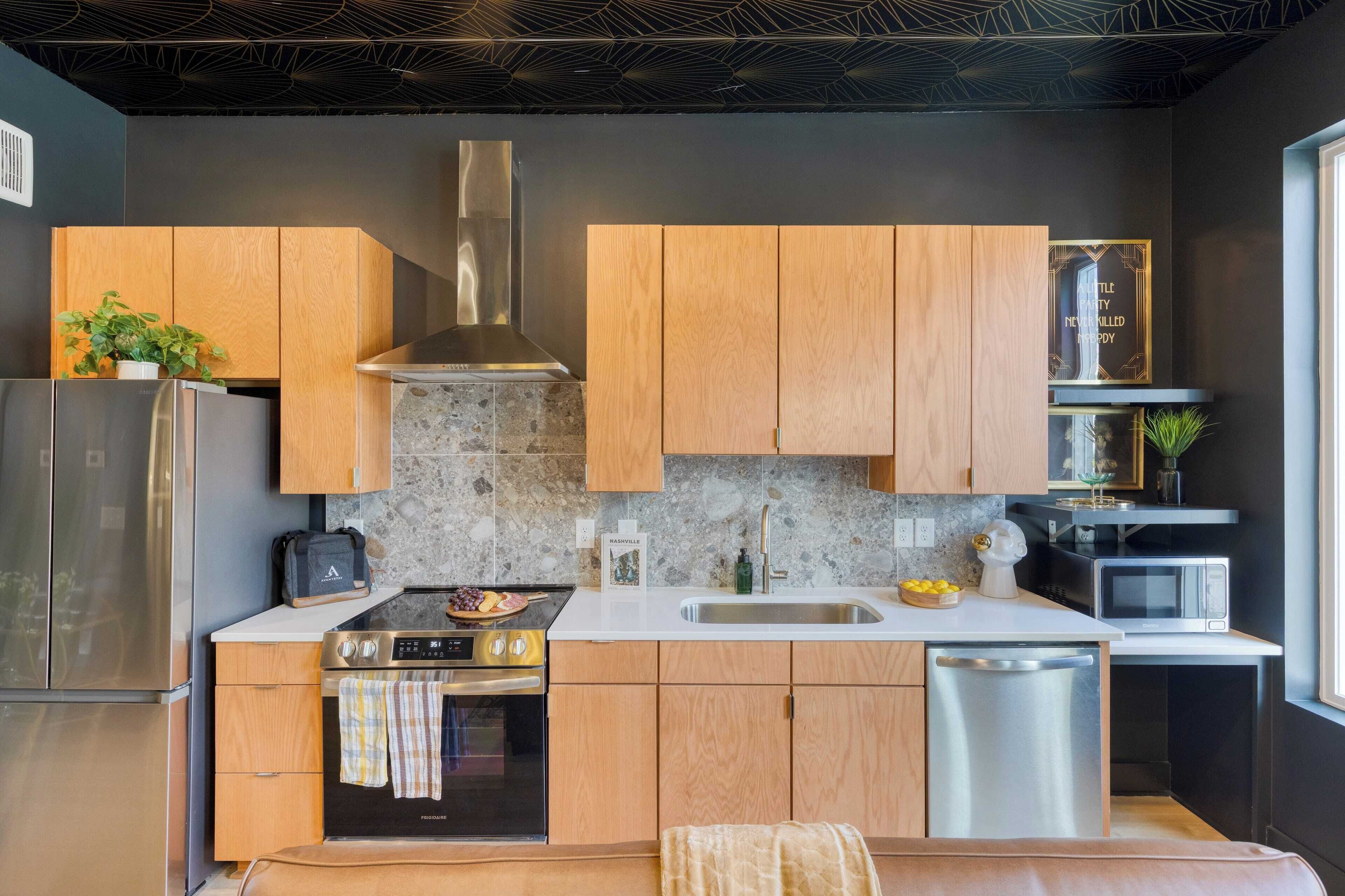 A modern kitchen with wooden cabinets, a stainless steel range, a built-in oven, and a microwave.