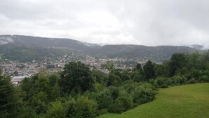 A view of a town nestled in a valley with a backdrop of hills and a cloudy sky. - Apartment on the heights of Gérardmer with a superb view (Gérardmer)