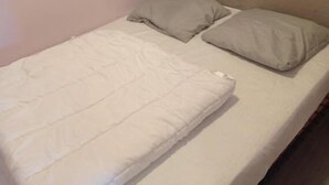 A single bed with a wooden headboard in a room with light pink walls. - Apartment on the heights of Gérardmer with a superb view (Gérardmer)
