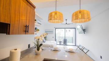 Een moderne keuken met houten kastjes, een centraal eiland met een bloevas, en twee hangende wilgentrossenlampen.