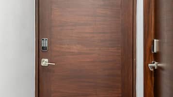 Une porte en bois dotée d’un clavier pour ouvrir la serrure, une enseigne au-dessus et une poignée de porte.
