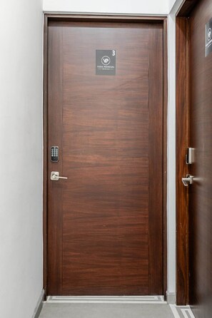 A wooden door with a keypad lock, a sign above it, and a door handle.