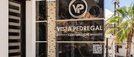 A modern building entrance with a sign for Vista Pedregal in Cabo San Lucas.