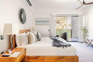 A hotel room with a bed, a nightstand, a lamp, a view of the outside, and a ceiling fan.