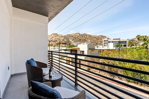 A balcony with wicker furniture and a view of a hillside.