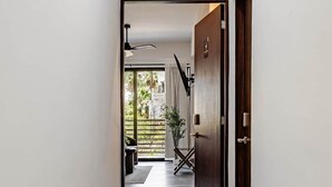 Un couloir au design moderne, qui mène à une pièce offrant une vue sur la verdure environnante.