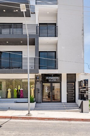 A modern building with a storefront labeled 'ELEMENTS Real Estate.'