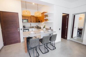 A modern kitchen with a central island, bar stools, and hanging wicker pendant lights.