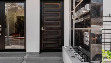 Une entrée moderne avec une porte en bois foncé, un hall d’entrée en verre et une enseigne indiquant « VISTA REDRIAL ».