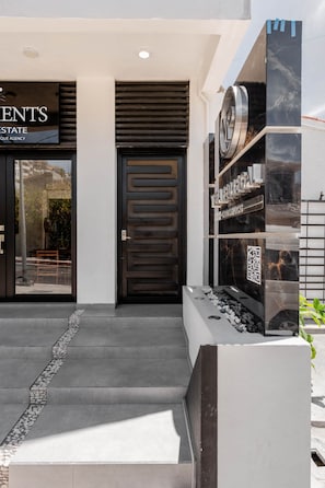 A modern building entrance with a dark wooden door, a glass entrance, and a sign for 'VISTA REDRIAL'.