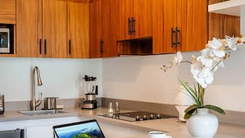 Een moderne keuken met houten kastjes, een inbouw eiland, een laptop, een koffiekop en een vaas met bloemen.