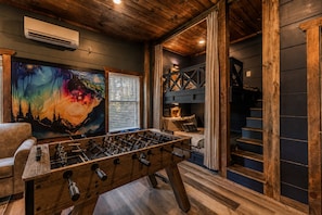 A cozy room with a foosball table, a painting, and a staircase leading to an upper level.