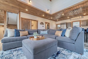 Un salon moderne avec un canapé d’angle, une table basse en bois et un tapis à motifs.