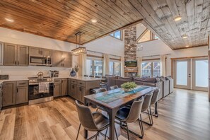Une cuisine spacieuse équipée d’appareils modernes, un coin repas avec une grande table et un espace salon confortable.