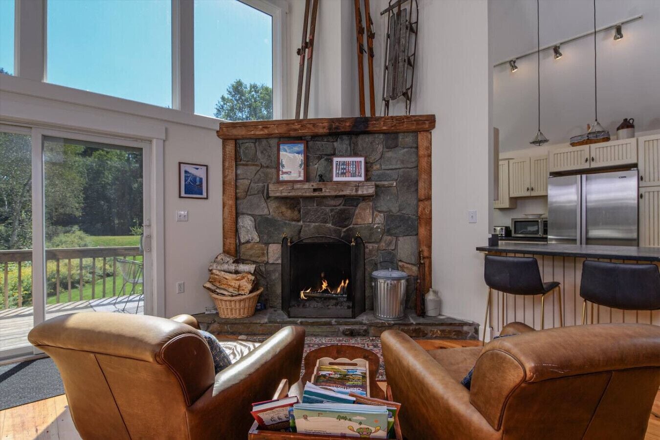A cozy living room with a stone fireplace, leather armchairs, and a view of the outdoors.