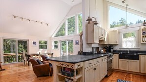 A spacious kitchen with a large island, wooden cabinets, and a dining area with a view of the outdoors.