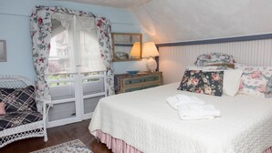 A bedroom with a bed, a dresser, a chair, and a window with curtains.
