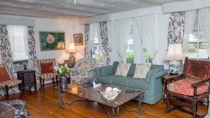 A cozy living room with a blue sofa, a wooden coffee table, and floral curtains.