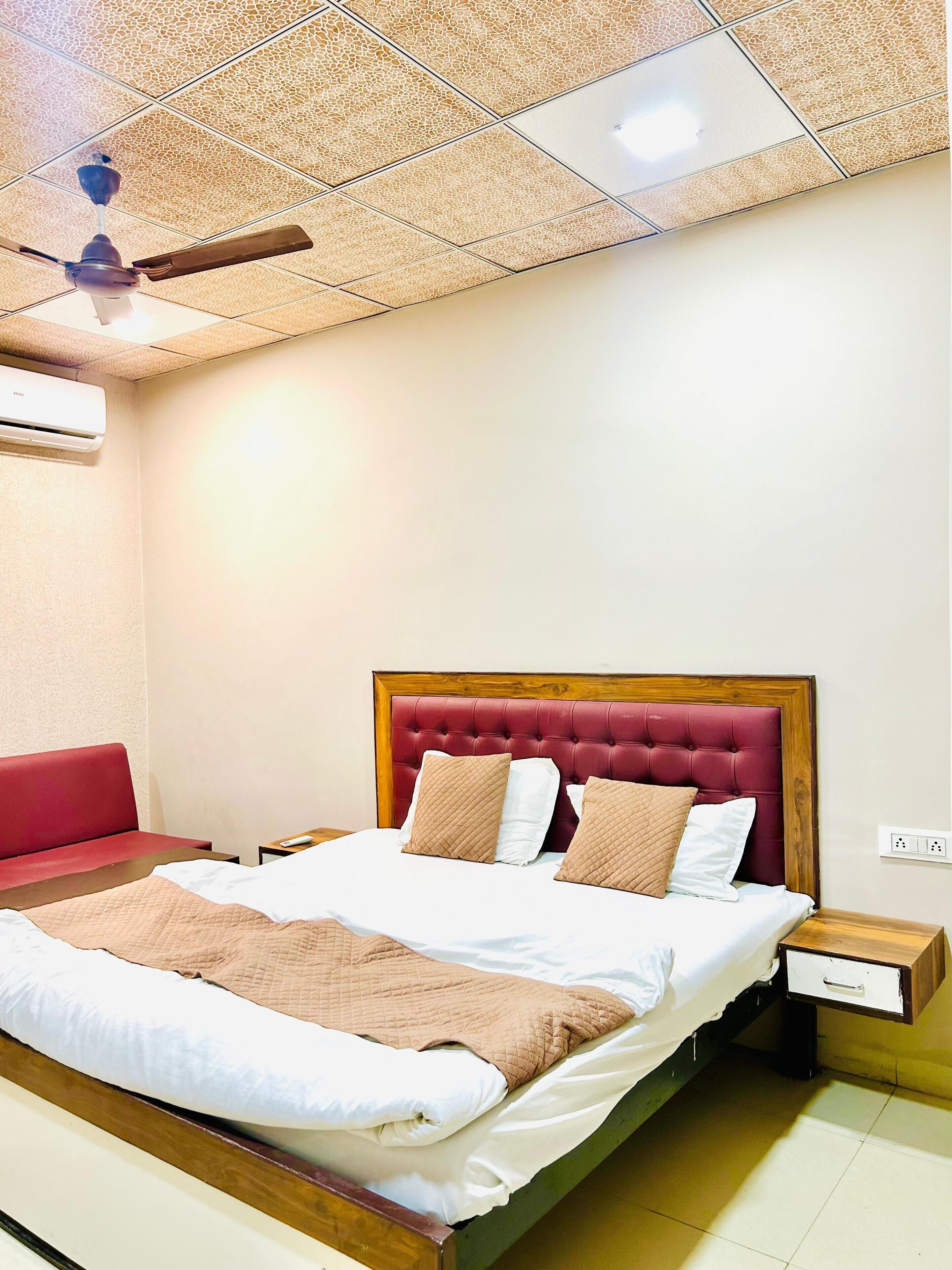 Un dormitorio con una cama, un sofá rojo, un ventilador de techo y un equipo de aire acondicionado.