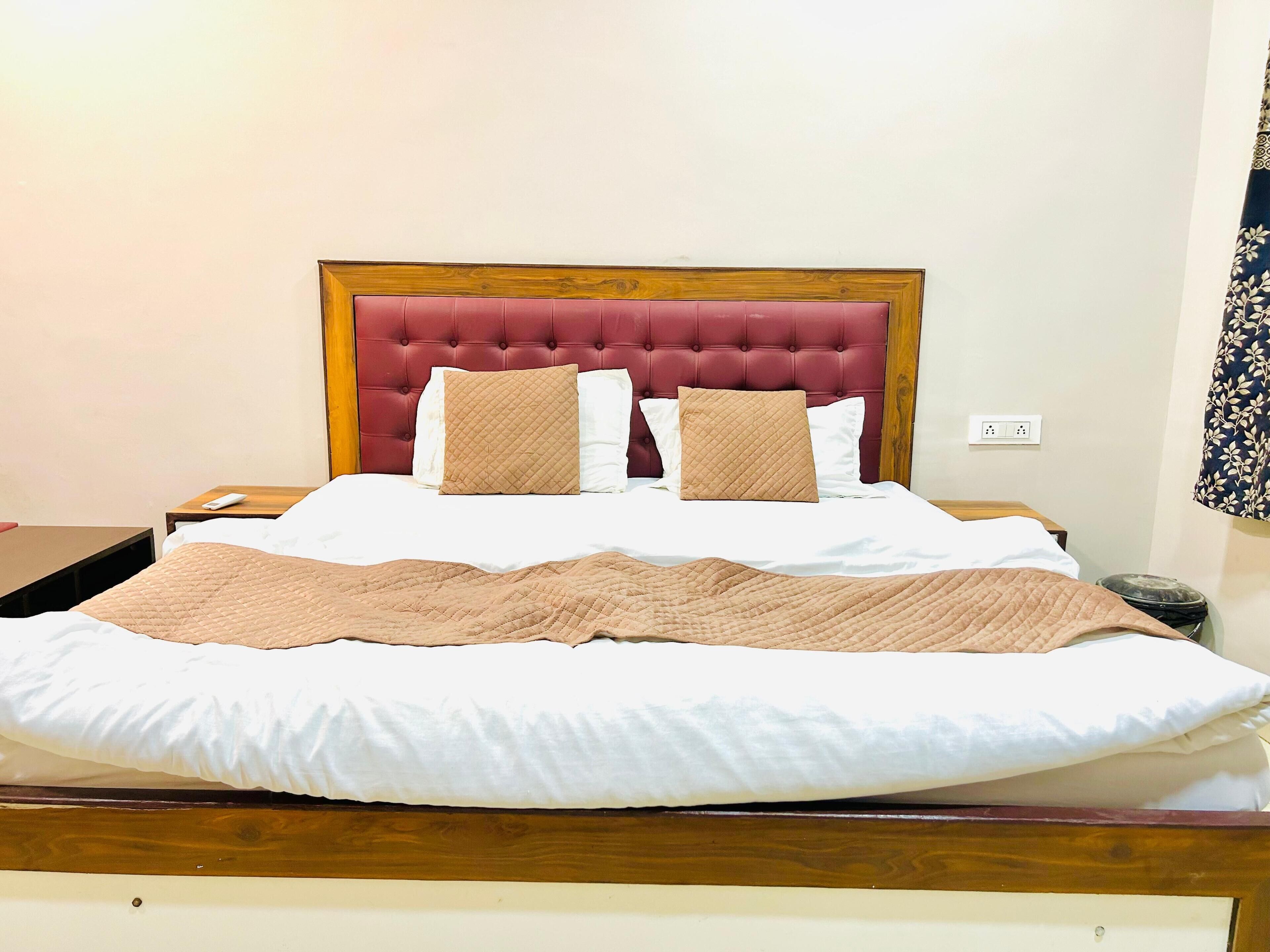 A neatly made bed with a wooden headboard, white bedding, and two beige pillows.