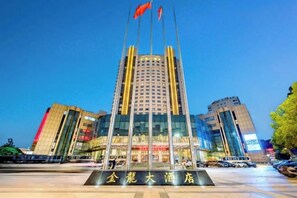 A hotel with a modern facade, a prominent entrance, and a flagpole with flags.