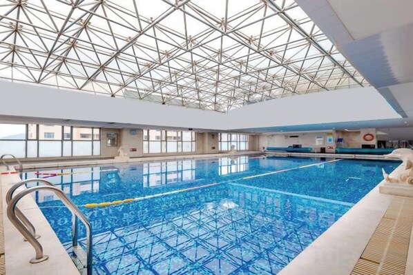 An indoor swimming pool with a high ceiling and large windows.