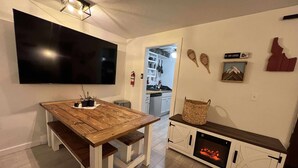Una cocina moderna con una mesa de comedor de madera, una chimenea empotrada y un televisor de pantalla plana montado en la pared.
