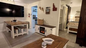 Una sala de estar moderna con una mesa de comedor de madera, una chimenea y un televisor montado en la pared.