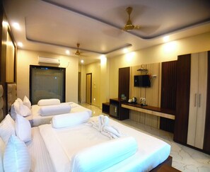 A hotel room with two beds, a TV, a minibar, and a ceiling fan. - Coral Beach Resort Mandarmoni (Kanthi)