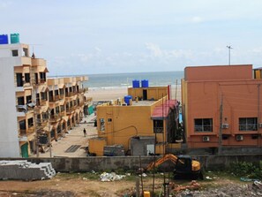 A construction site with buildings, an excavator, and a beach in the background. - Coral Beach Resort Mandarmoni (Kanthi)