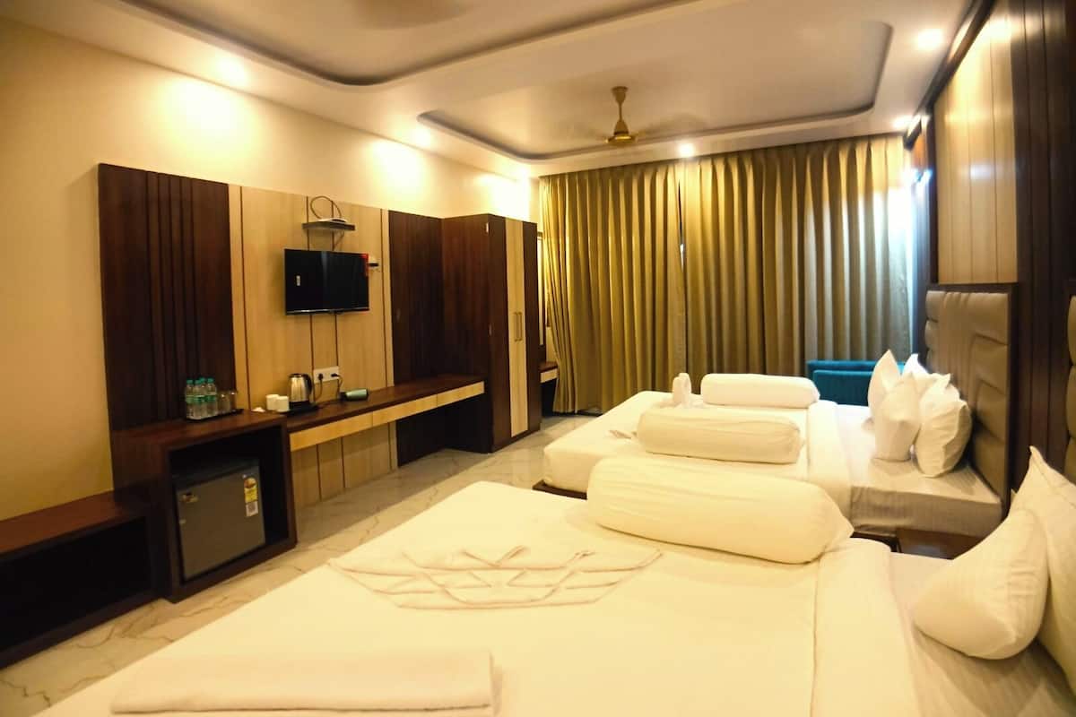 Habitación de hotel con dos camas, televisor, minibar y ventilador de techo.