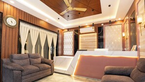 A modern reception area with a marble reception desk, two sofas, a ceiling fan, and wooden paneling.