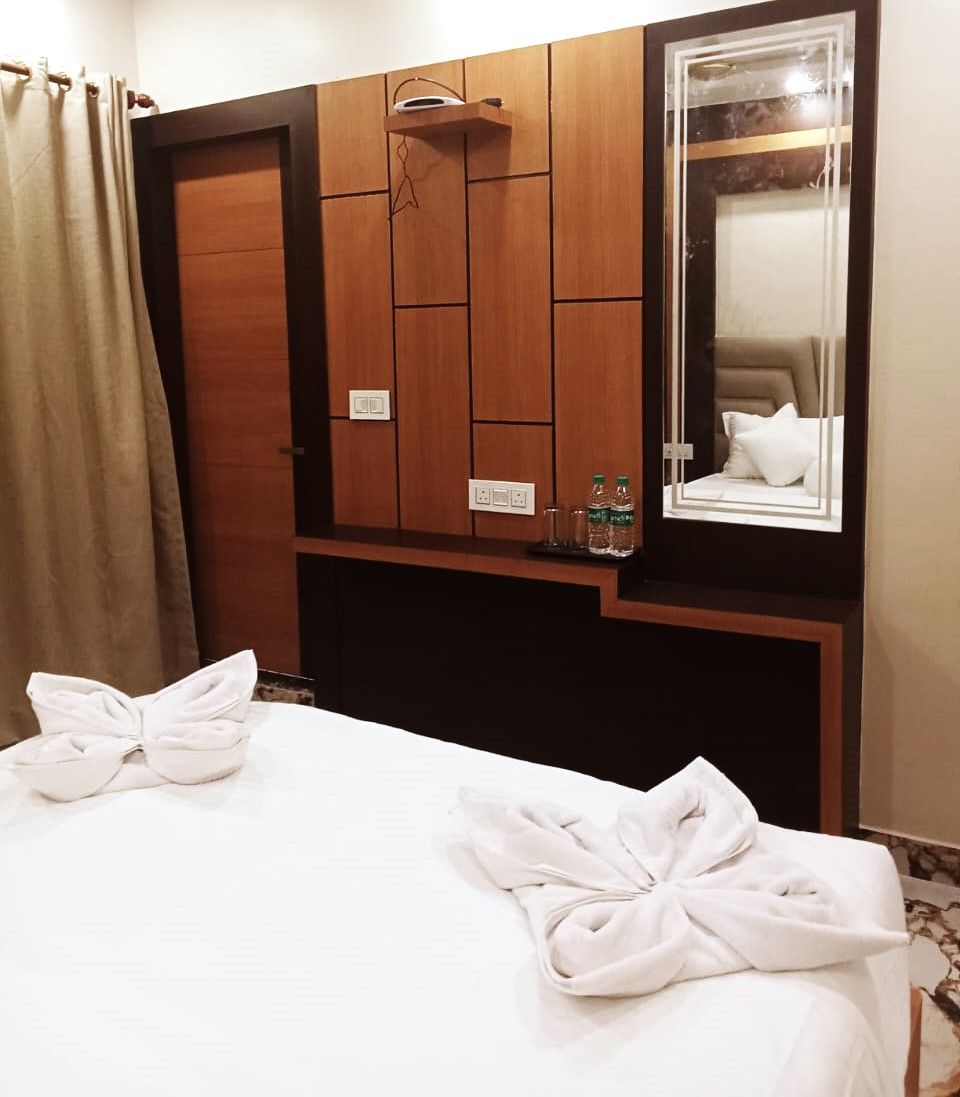 Een hotelkamer met een bed, een houten garderobe, een spiegel en een handdoek op het bed.