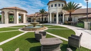 Une cour avec une fontaine, des sièges en plein air et un bâtiment orné d’arcades.