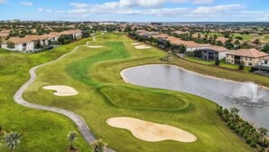 Un parcours de golf avec des bunkers, un obstacle d’eau et des immeubles résidentiels en arrière-plan.