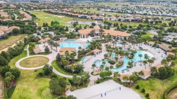 Vue aérienne d’un complexe hôtelier doté de plusieurs piscines, de palmiers et, au loin, d’un terrain de golf.