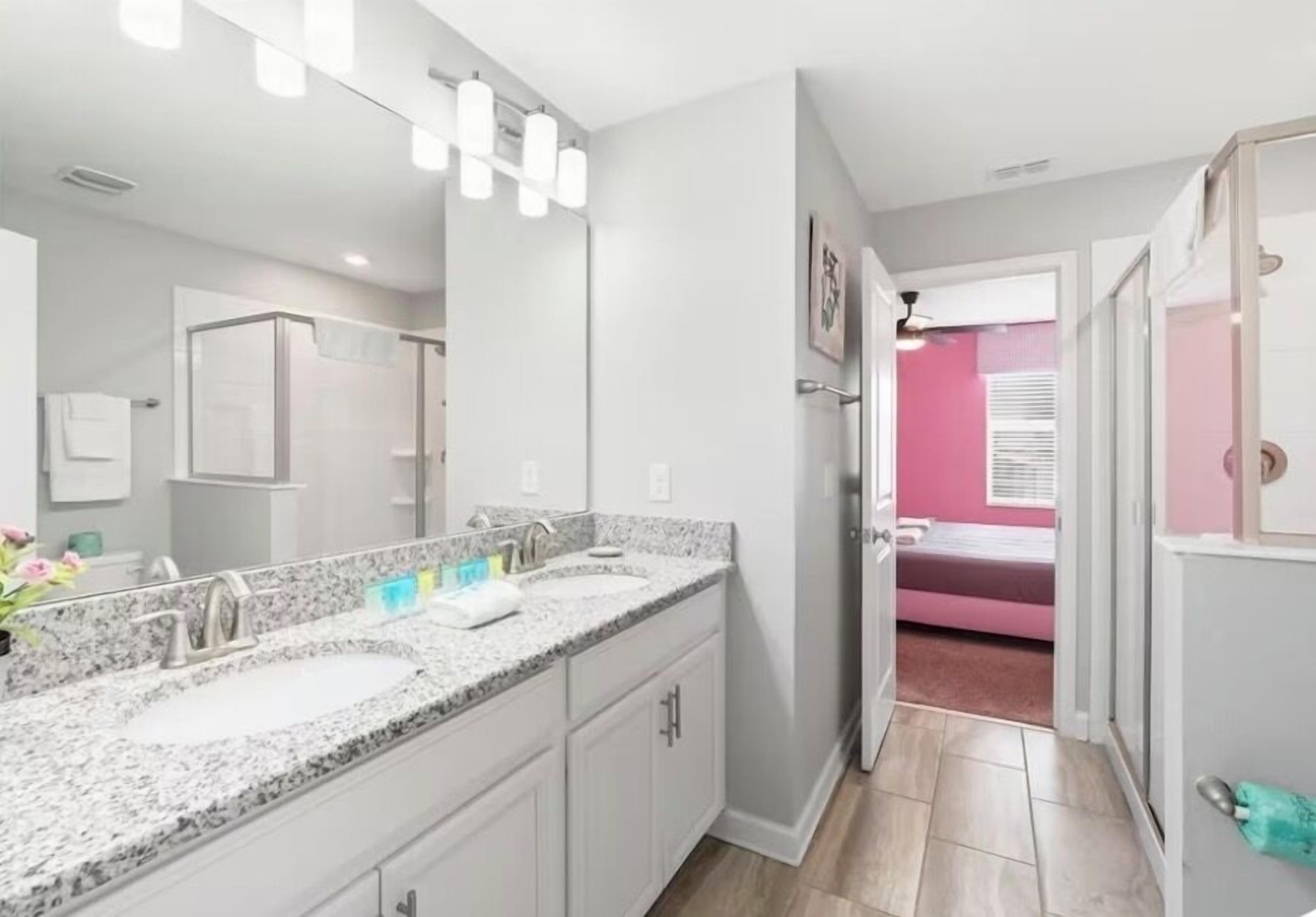 A modern bathroom with a granite countertop, a large mirror, and a walk-in shower.
