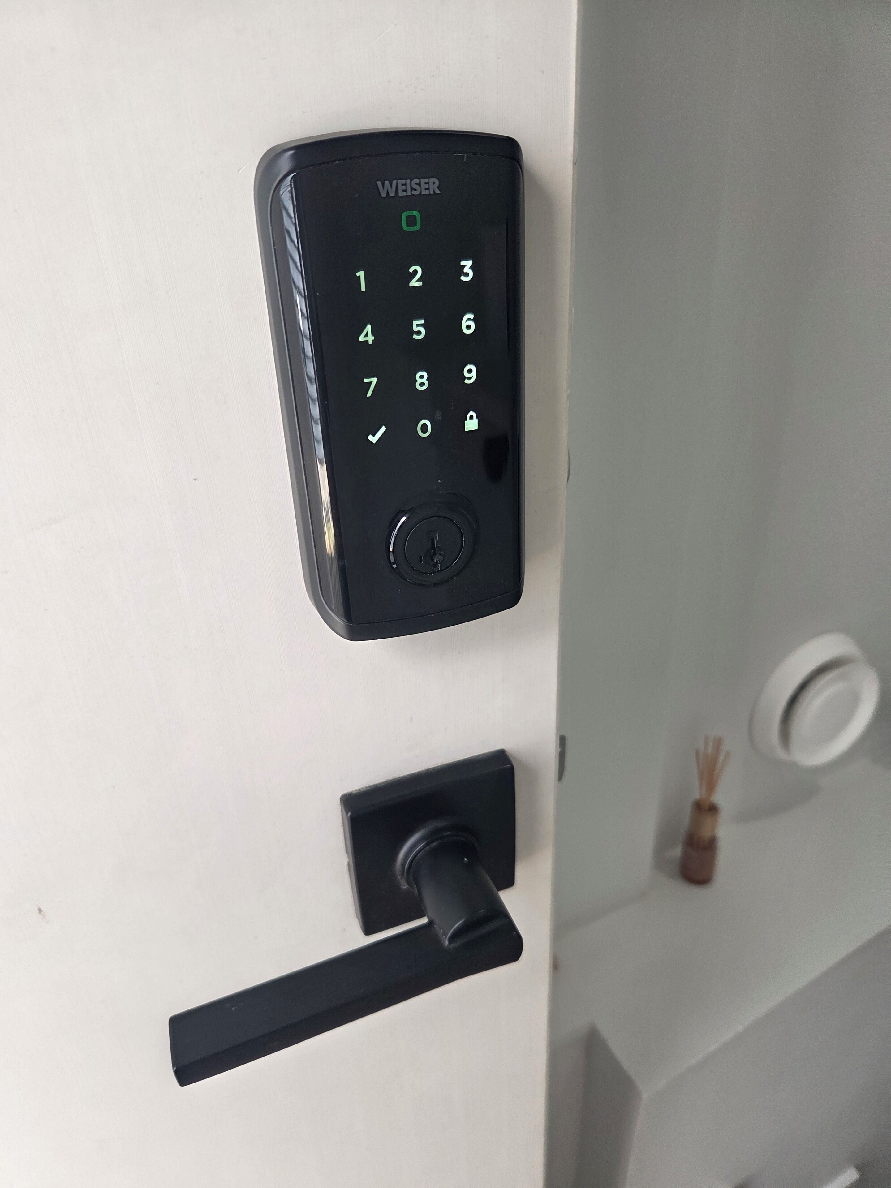 A black door lock with a keypad and a keyhole.