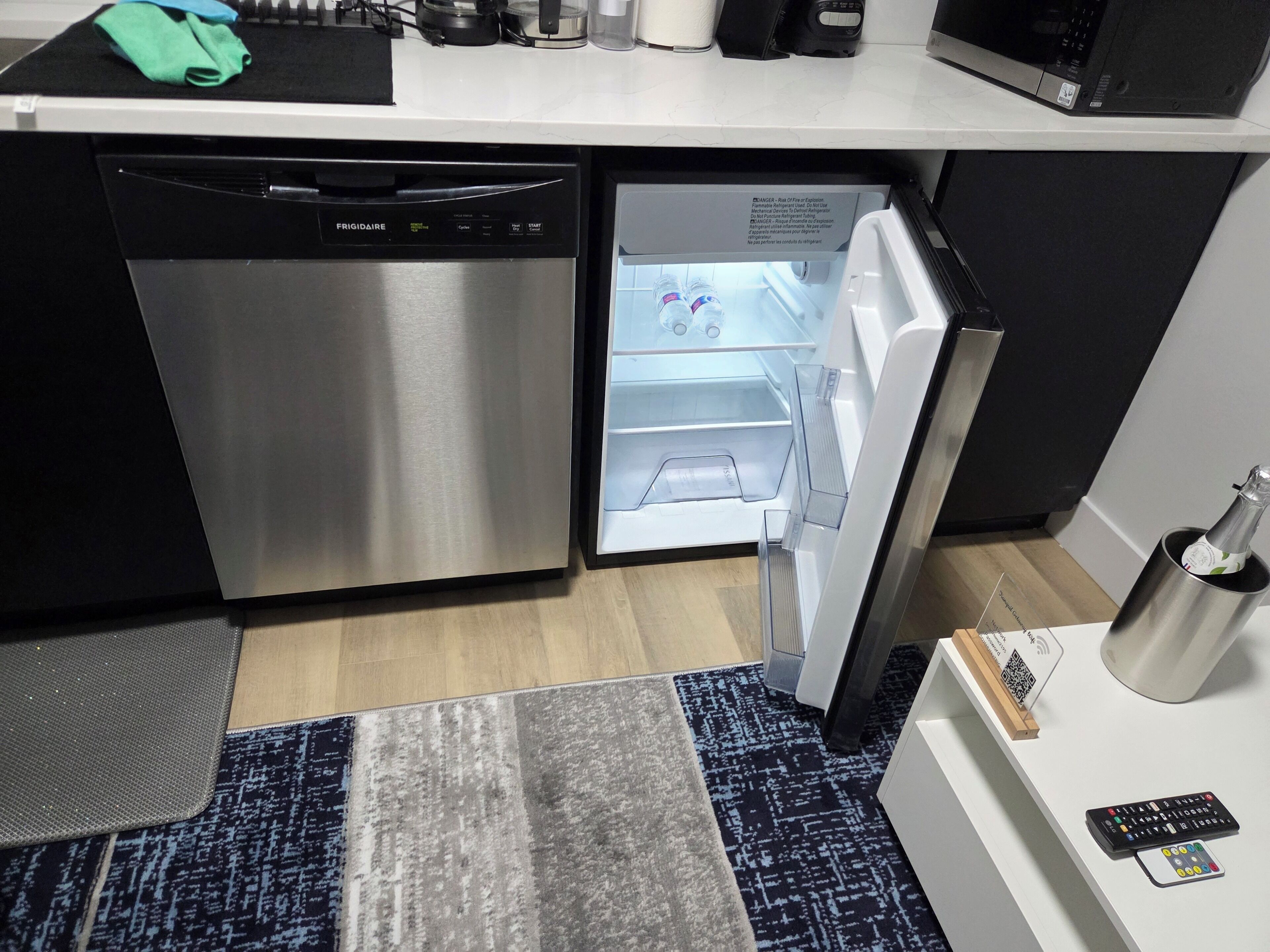 A compact kitchen with a built-in dishwasher, a refrigerator, and a microwave.