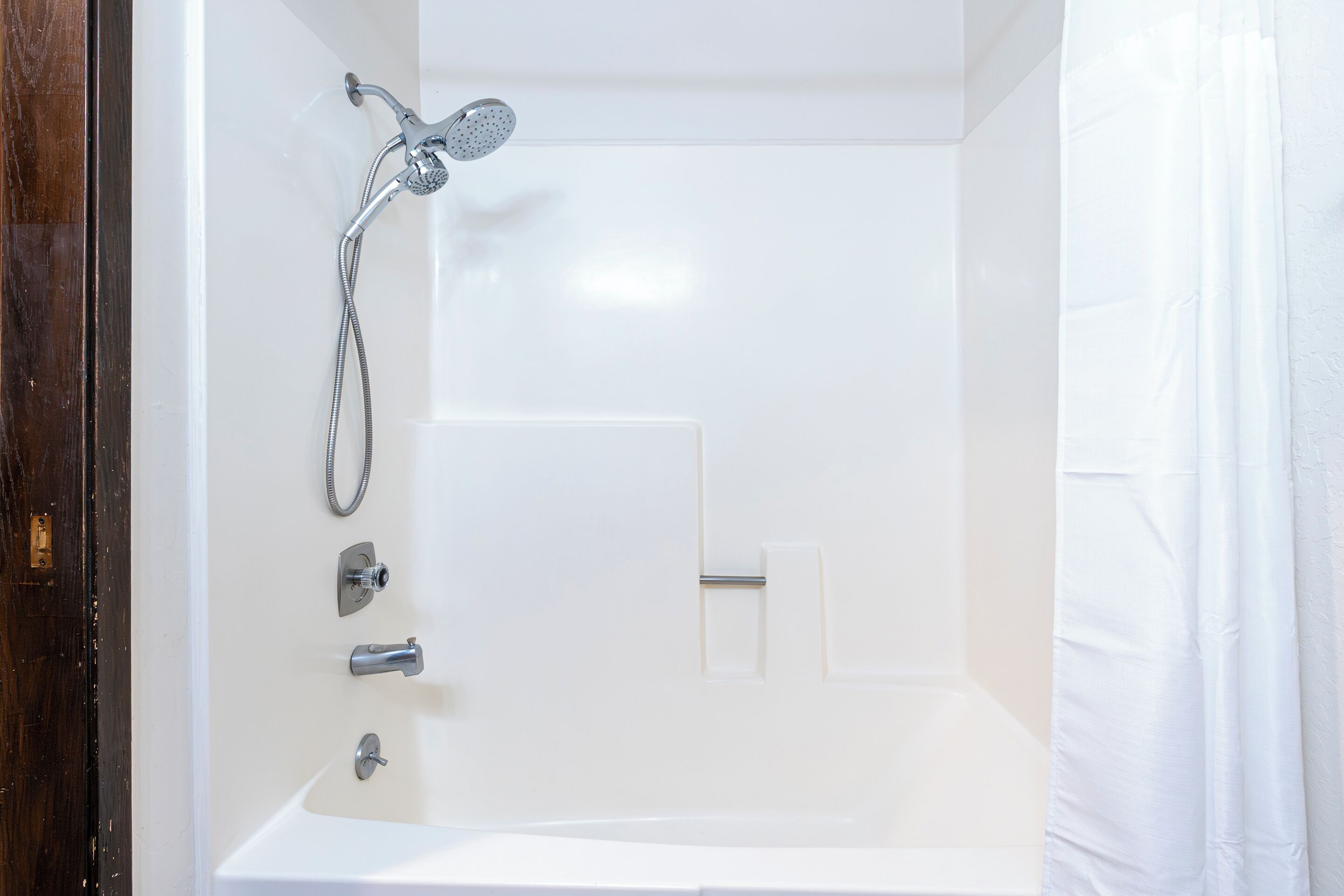 A modern bathroom with a bathtub, a showerhead, and a toilet.